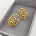 Gros plan détaillé de boucles d'oreilles spirales dorées vintage dans un écrin gris. - Or