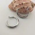 Gros plan de boucles d'oreilles créoles en métal argenté lisse, style élégant et polyvalent. - 30mm Diamètre / Argent