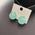 Boucles d'oreilles minimalistes rondes vert clair sur carte de présentation, bijoux simples. - Bleu clair