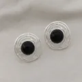 Gros plan detail de boucles d'oreilles rondes en metal vintage avec agate noire lisse. - Aiguille en argent