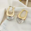 Élégantes boucles d'oreilles pendantes dorées en U avec base texturée claire, style chic. - Or/Transparent