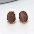 Gros plan détaillé de boucles d'oreilles ovales irrégulières violettes à bordure dorée. - Pierre d'Œil de Chat Violette