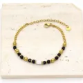 Detailed view of gold titanium steel bracelet featuring black stones and a freshwater pearl. - Black
