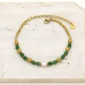 Detailed view of golden titanium steel bracelet with green stones and a freshwater pearl - Green