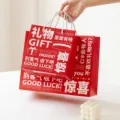 Rote Papiertragetasche mit weissem Aufdruck, ideal als romantische Geschenktuete fuer Feste. - Überraschungsgeschenk / L