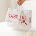 Weisse Papiertragetasche mit rotem Geburtstagsschriftzug, elegante Geschenkverpackung. - Alles Gute zum Geburtstag / L