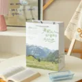 Bolsa de regalo de papel con hermoso paisaje estetico y texto inspirador para flores y compras. - No te quedes atrapado en tierra sin viento - Tamaño grande