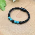 Primo piano del bracciale in pelle intrecciata nera con perline turchesi e chiusura magnetica. - Turchese Blu (XL0931-3)