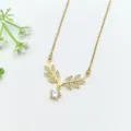 Primo piano di una delicata collana con ciondolo a foglia dorata e zirconi cubici lucidi. - Stile Pendente Geometrico Foglia (XL1200-311)