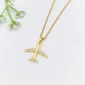 Primo piano della collana con ciondolo aereo dorato con pietre di zircone scintillanti sulle ali. - Stile Aereo (XL1200-374) / Oro