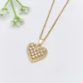 Squisito primo piano di una collana con ciondolo a cuore in zircone dorato, dettaglio chic. - Stile Cuore Vuoto (XL1200-444)
