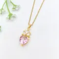 Primo piano dettagliato di una collana dorata con pendente in cristallo a cuore rosa e zirconi. - Stile Mini Corona Squisita (XL1200-332)