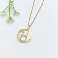 Primo piano dettaglio di una collana in acciaio dorato con ciondolo luna e coniglio in cristallo. - Stile Luna Orecchio di Coniglio (XL1200-497)