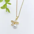 Primo piano di una collana placcata in oro con zirconi scintillanti e pendente di perla bianca. - Stile Perla Fiore Farfalla (XL1200-43)