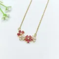 Primo piano dettagliato della collana con ciondolo floreale in zircone dorato e pietre rosse. - Stile Pendente Piccolo Fiore Rosso (XL1200-312)