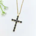 Primo piano della collana con ciondolo a croce dorata con zirconi neri scintillanti a goccia. - Croce in Zirconia Nera (XL2606-091)