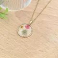 Primo piano dettaglio della catena placcata in oro e del ciondolo rotondo in resina di fiori. - Stile Tondo Floreale Rosa Giallo Bianco (XL2171-02)