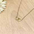 Close-up shot of an elegant gold interlocking double heart pendant necklace on wooden background. - XL1338-06 Gold
