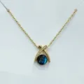 Primo piano della collana con ciondolo a croce dorata con perla blu scintillante cielo stellato. - Stile Sfera Cielo Stellato Incrociato (XL1470-150)