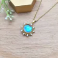 Dettaglio di una collana dorata con ciondolo a sole e pietra centrale azzurra. - Stile Girocollo Sole Oro (XL1992-90 Oro + Catena a Croce)