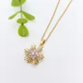 Gold snowflake pendant necklace detailed view with sparkling pink zirconia stones on fine chain. - Gold Snowflake