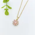 Detail shot of a gold flower necklace pendant featuring sparkling pink crystal stones. - Gold Pink Zirconia Flower