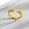 Dettaglio di un anello incrociato in acciaio al titanio con strass scintillanti. - Taglia 6 / Oro
