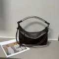 Detailed view of luxury dark brown leather shoulder bag with unique handmade woven handle design. - Blank / Coffee