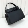 Detailed view of the black leather top handle bag showcasing premium texture and hardware. - Black