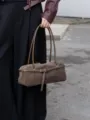 Primo piano della borsa a spalla retrò in camoscio marrone con spallacci sottili e cintura. - Grigio