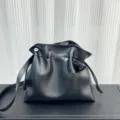 Primer plano del bolso saco de piel suave negra con nudos laterales delicados y detalles finos. - Negro