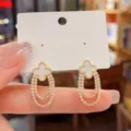 Nahaufnahme von Kleeblatt Strass Doppelcreolen mit exzellenter Handwerkskunst und Glanz. - Weiß