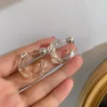 Close-up of clear irregular geometric resin hoop earrings with silver-tone ball back design. - White Transparent