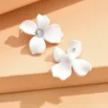 Detail view of minimalist white four-petal flower stud earrings with dazzling crystal center. - White