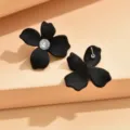 Black matte flower stud earrings detail with central rhinestone and metal post view. - Black