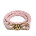 Nahaufnahme des eleganten rosa geflochtenen Ledergürtels mit stilvoller Metallknotenschnalle. - Lotusrosa