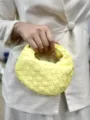 Detailed close-up view of the vibrant yellow woven leather bag handle and craftsmanship details. - Yellow