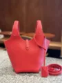 Red leather bucket bag close-up showing premium texture and white stitching details. - S / Red