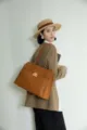 Detailed shot of women's genuine leather commuter shoulder bag with metal lock design. - Toffee Gold