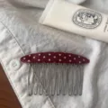 Detail shot of a red polka dot acetate hair comb with metal tines resting on white fabric. - Retro Red and White Polka Dot