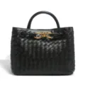 Black woven leather top handle bag with elegant gold metal knot hardware detail for women. - Black