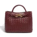 Burgundy woven leather handbag detail with elegant metallic knot closure and fine texture. - Burgundy