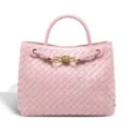 Detailed close-up view of the pink woven leather handbag featuring elegant gold knot hardware. - Lotus Pink