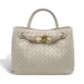 Detail shot of light grey woven leather handbag with elegant metal knot hardware and handle. - Sand White