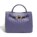 Purple woven leather handbag with gold metal knot detail, elegant luxury tote bag close-up. - Purple