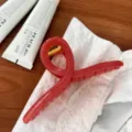 Detailaufnahme einer roten Gelee-Haarklammer in Kleiderbügelform auf Holztisch. - Kleiderbügel Schmetterlingsschnalle (HDJ-10) / Ca. 15cm / Gelee Erdbeerrosa