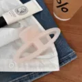 Vista detallada en primer plano de la pinza de pelo rosa semicírculo hueco en denim y camisa. - Blanco Gelatina