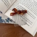 Close-up van een schildpad acetaat strik haar kam geplaatst op een open boek, detail weergave. - Amerikaanse Koffie - Acetaat Haarkam