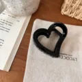 Detailaufnahme einer stilvollen schwarzen herzförmigen Haarklammer auf Stoff, Accessoire. - Herz Schmetterlingsschnalle / Hellschwarz