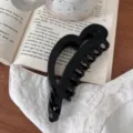Vista detallada de una pinza para el pelo negra en forma de corazón sobre libro y encaje. - 12.5cm / Negro Brillante